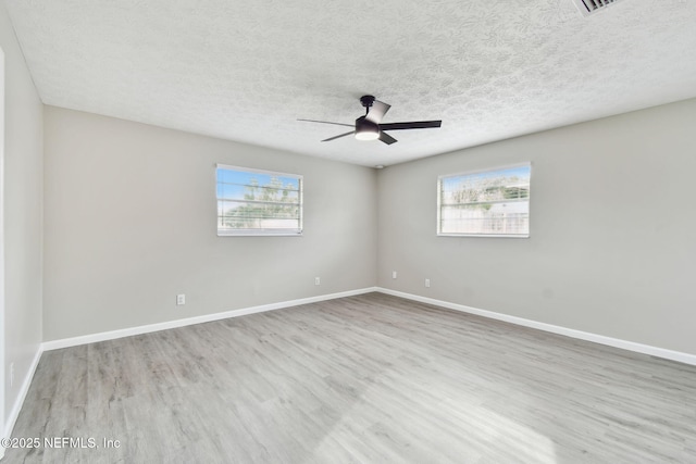 unfurnished room with ceiling fan, a textured ceiling, baseboards, and wood finished floors