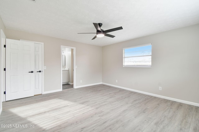 unfurnished bedroom with light wood-style flooring, baseboards, and a textured ceiling