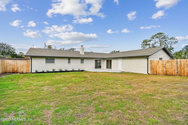 back of property with brick siding, fence, a lawn, a chimney, and a patio area