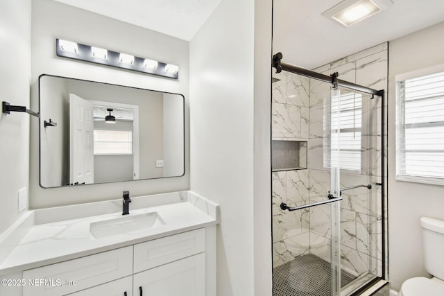 full bathroom featuring a marble finish shower, toilet, and vanity