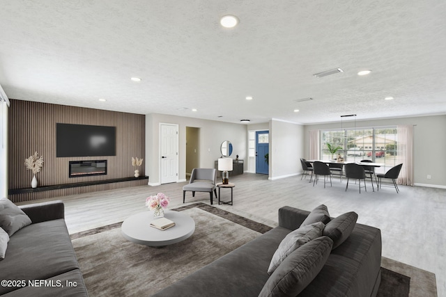 living room with recessed lighting, a textured ceiling, a large fireplace, and wood finished floors