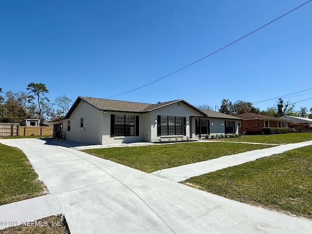 view of front of house featuring brick siding, a front yard, and fence