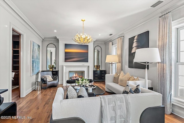 living room featuring hardwood / wood-style flooring, crown molding, and a chandelier