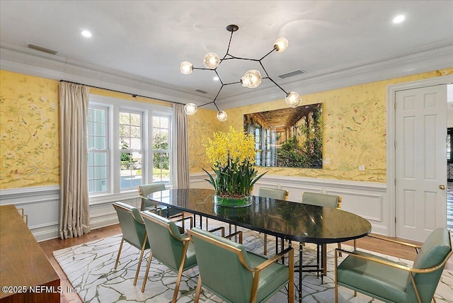 dining space with ornamental molding and light hardwood / wood-style floors