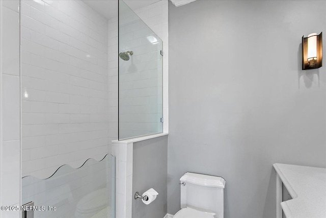 bathroom with toilet and a tile shower