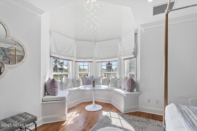 interior space featuring hardwood / wood-style flooring, breakfast area, ornamental molding, and an inviting chandelier