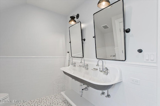 bathroom with toilet, tile walls, and sink