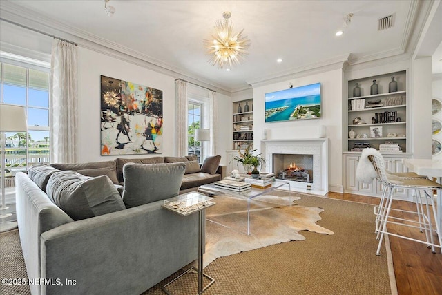 living room featuring plenty of natural light, built in shelves, a chandelier, and hardwood / wood-style floors