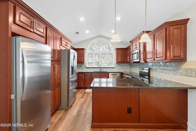 kitchen with sink, vaulted ceiling, appliances with stainless steel finishes, kitchen peninsula, and pendant lighting