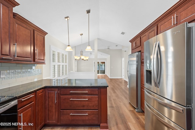 kitchen featuring tasteful backsplash, vaulted ceiling, pendant lighting, and stainless steel fridge