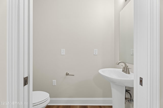 bathroom featuring toilet, sink, and hardwood / wood-style floors