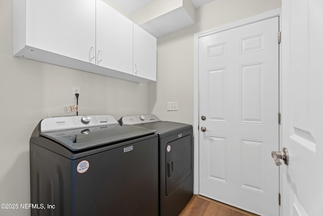 laundry room featuring dark wood-type flooring, washer and clothes dryer, and cabinets