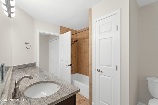 full bathroom featuring vanity, tiled shower / bath, and toilet