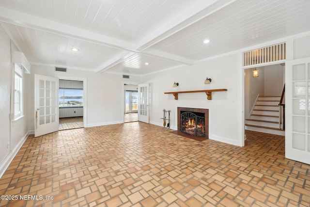 unfurnished living room featuring beam ceiling and french doors