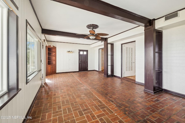 interior space featuring beamed ceiling, ceiling fan, and wood walls