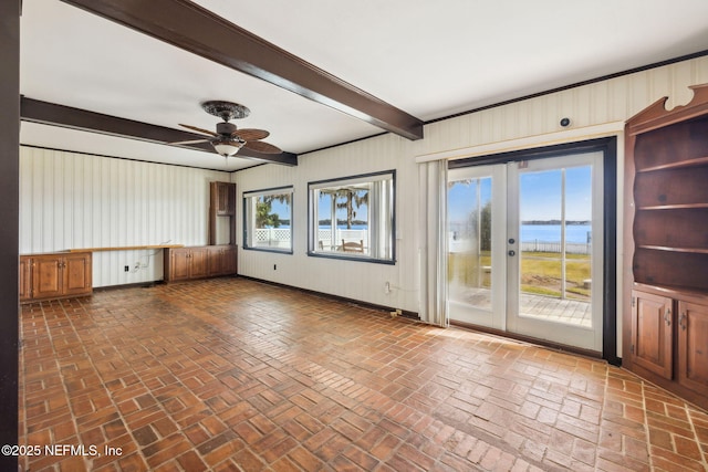 empty room featuring a water view, ceiling fan, and beam ceiling