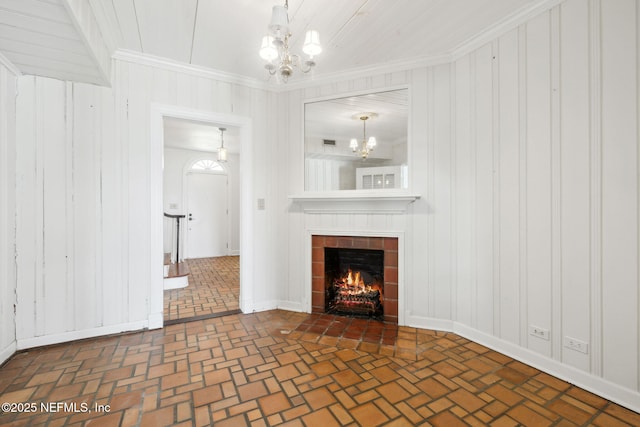 unfurnished living room featuring a notable chandelier, a fireplace, and ornamental molding