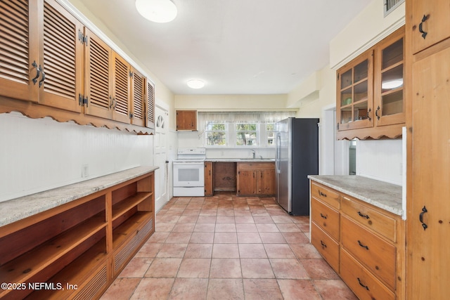 kitchen featuring sink, stainless steel fridge, light tile patterned floors, white range with electric cooktop, and light stone countertops