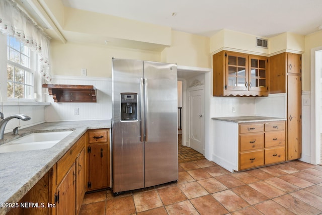 kitchen with sink, light stone countertops, and stainless steel fridge with ice dispenser