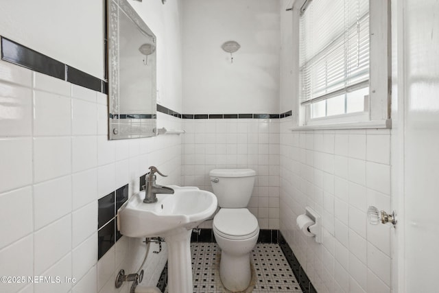 bathroom featuring toilet, tile patterned flooring, and tile walls