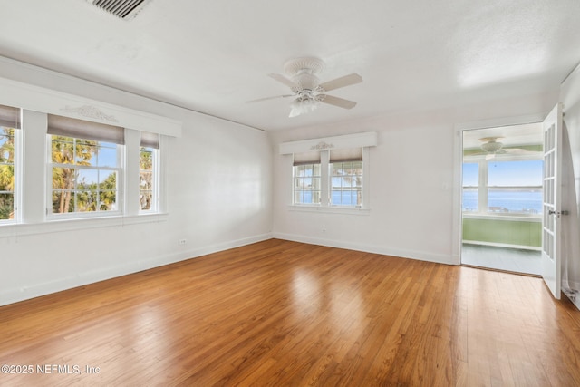 empty room with a water view, plenty of natural light, and hardwood / wood-style floors