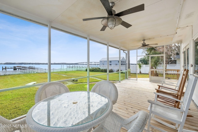 sunroom featuring ceiling fan and a water view