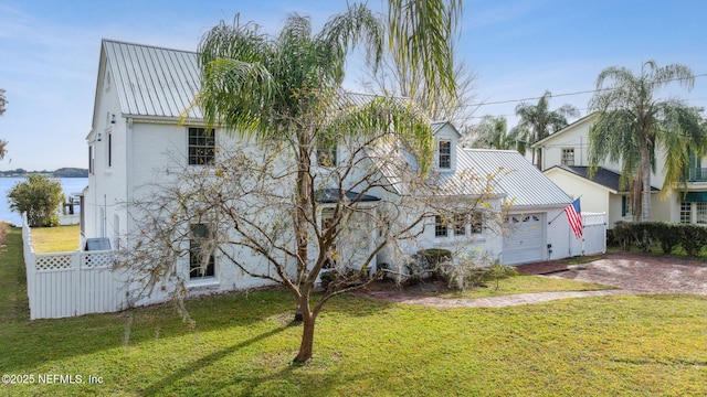 view of front of home featuring a garage, a front lawn, and a water view