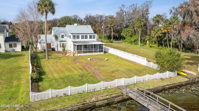 rear view of property with a water view, a sunroom, and a lawn