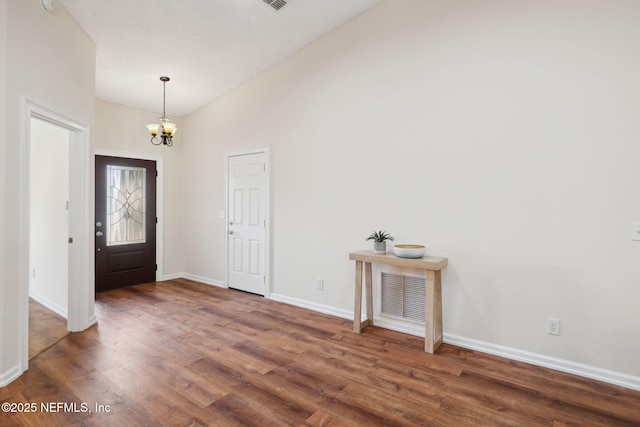 entrance foyer featuring dark wood-type flooring, lofted ceiling, and an inviting chandelier