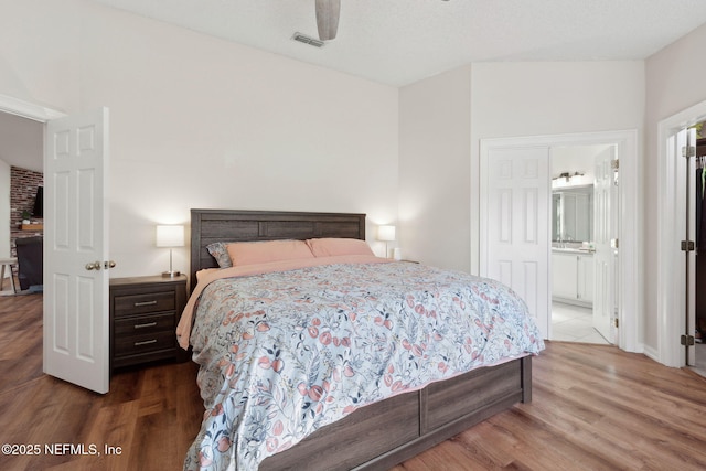 bedroom with ceiling fan, connected bathroom, and hardwood / wood-style floors