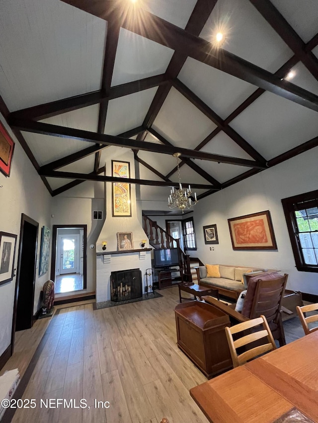 living area featuring a chandelier, a fireplace, high vaulted ceiling, and light wood finished floors