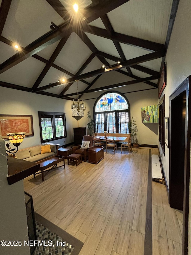 unfurnished living room with high vaulted ceiling, beamed ceiling, and light wood-style flooring