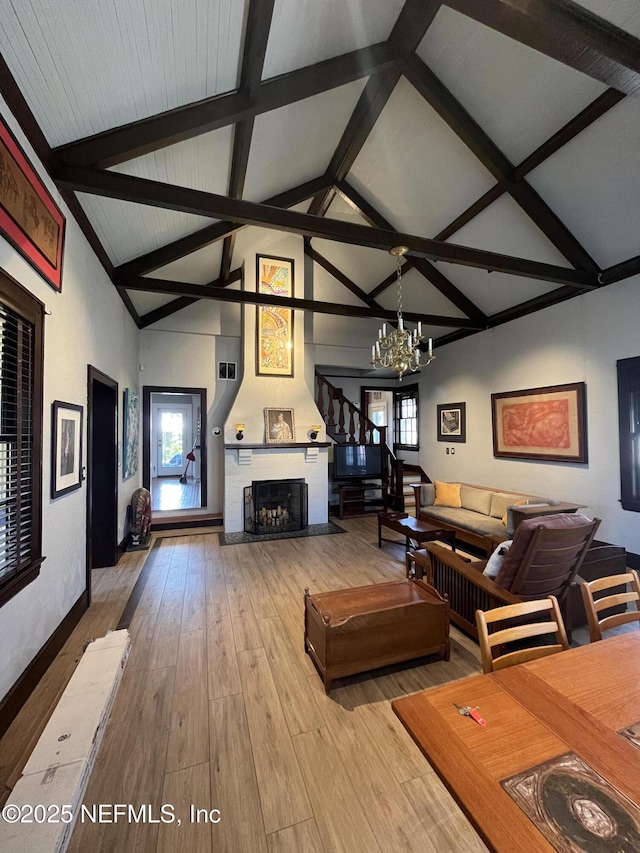 unfurnished living room with a large fireplace, a chandelier, wood-type flooring, high vaulted ceiling, and beam ceiling