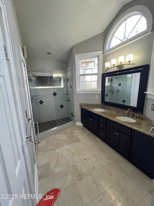 bathroom featuring a stall shower, lofted ceiling, and a sink