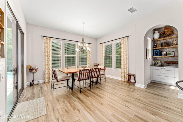 dining area with light hardwood / wood-style flooring and a notable chandelier