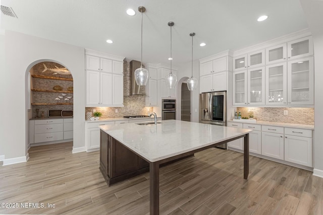 kitchen featuring white cabinetry, appliances with stainless steel finishes, and an island with sink