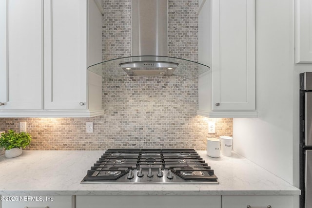 interior details featuring white cabinetry, light stone countertops, stainless steel gas cooktop, and wall chimney exhaust hood