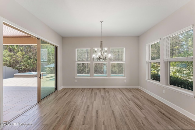 unfurnished dining area with an inviting chandelier, plenty of natural light, and light hardwood / wood-style floors