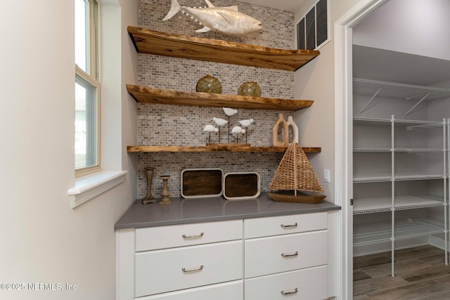 bar featuring wood-type flooring, white cabinets, and decorative backsplash