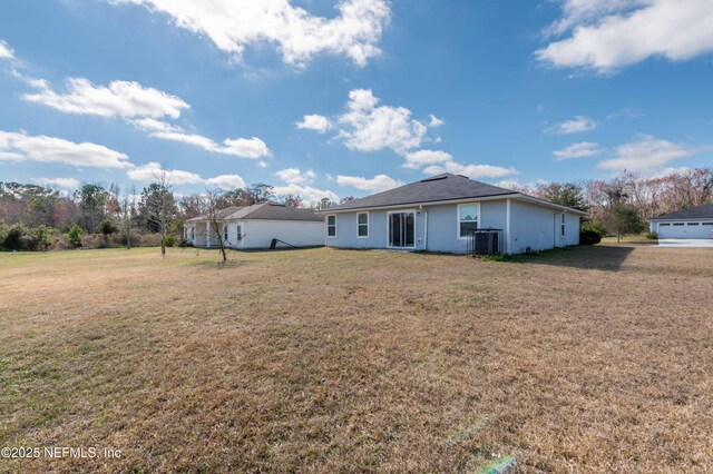 rear view of house with cooling unit and a lawn