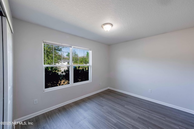 empty room with baseboards, a textured ceiling, and dark wood-style floors