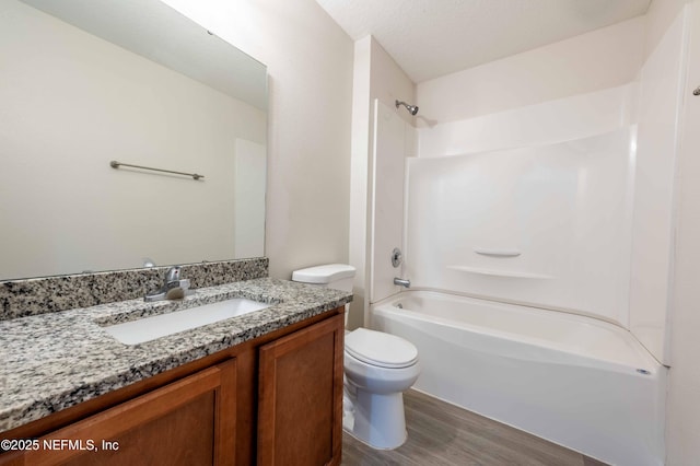 bathroom with vanity,  shower combination, toilet, and wood finished floors