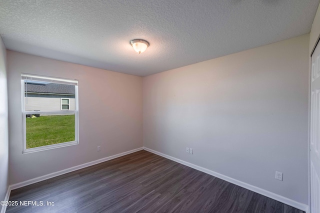 spare room featuring a textured ceiling, dark wood-type flooring, and baseboards