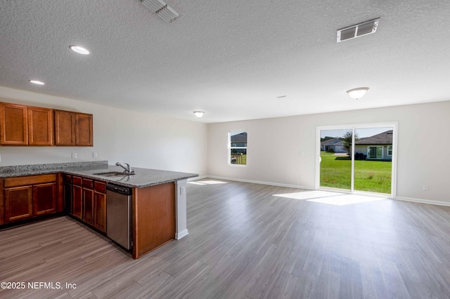 kitchen featuring visible vents, a sink, open floor plan, a peninsula, and dishwasher