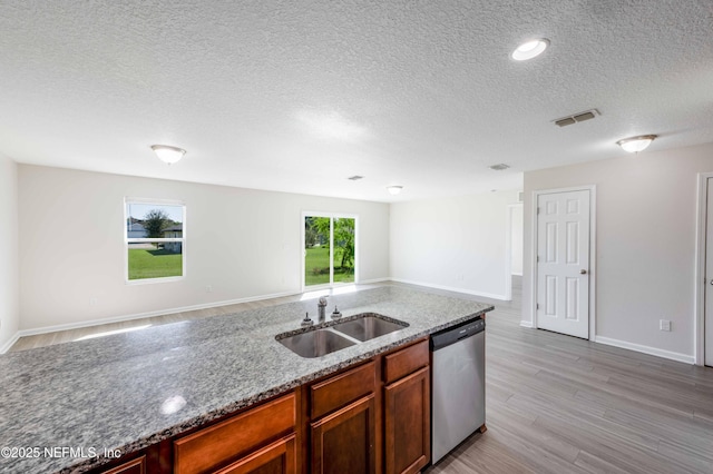 kitchen featuring light wood finished floors, visible vents, light stone countertops, dishwasher, and a sink