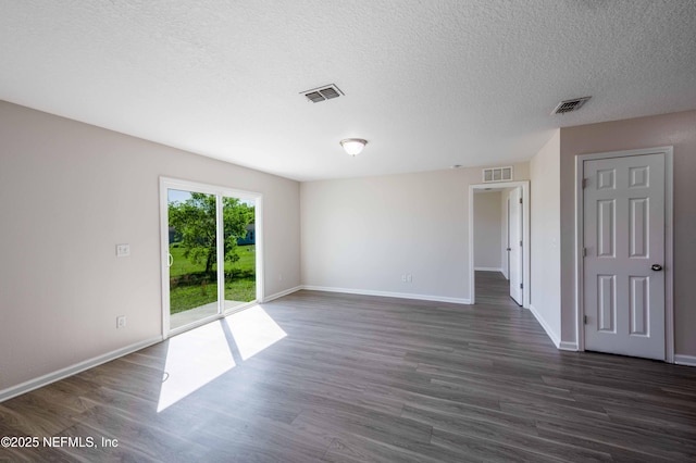 spare room featuring dark wood-type flooring, baseboards, and visible vents