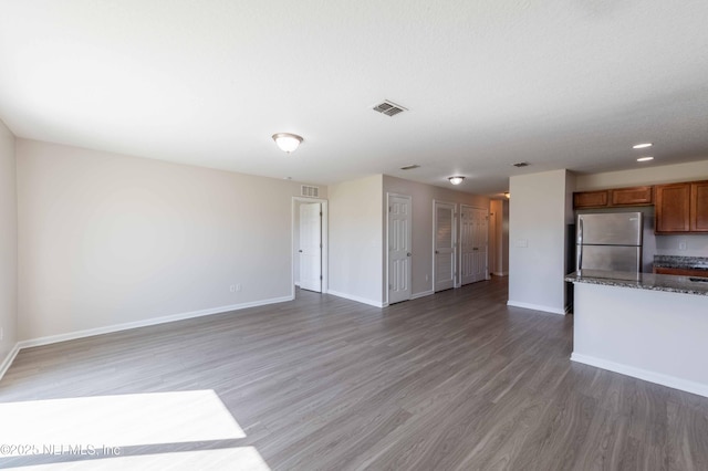 unfurnished living room featuring visible vents, baseboards, and light wood finished floors