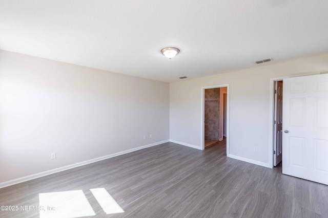 spare room with visible vents, baseboards, and wood finished floors