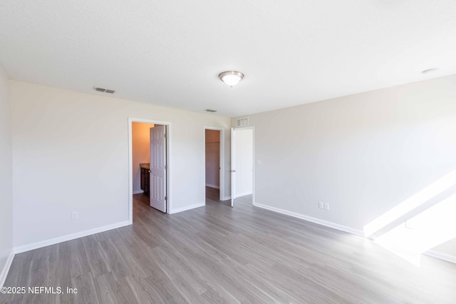 unfurnished room featuring wood finished floors, visible vents, and baseboards