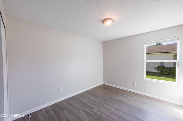 spare room with wood finished floors, baseboards, and a textured ceiling